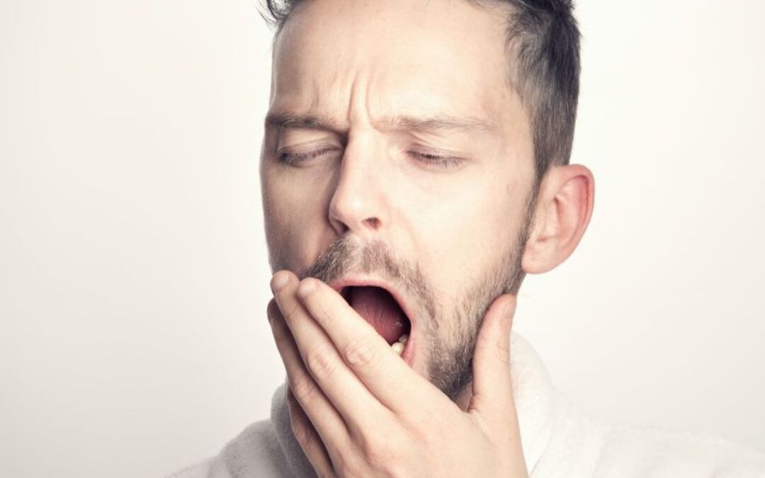 white man yawning with hand partially covering mouth